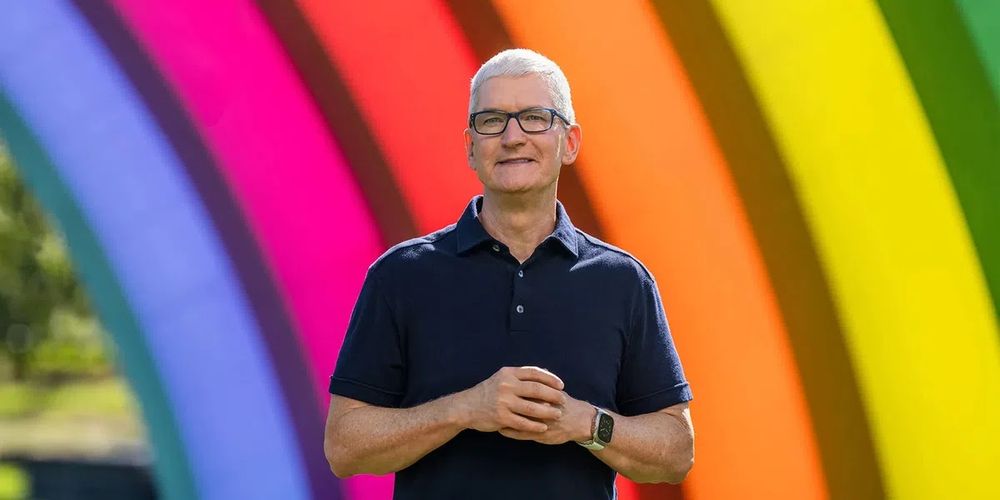 Tim Cook standing under rainbow colored arches in Apple Park, where he always stands during Apple's infomercial-style product launch videos. 