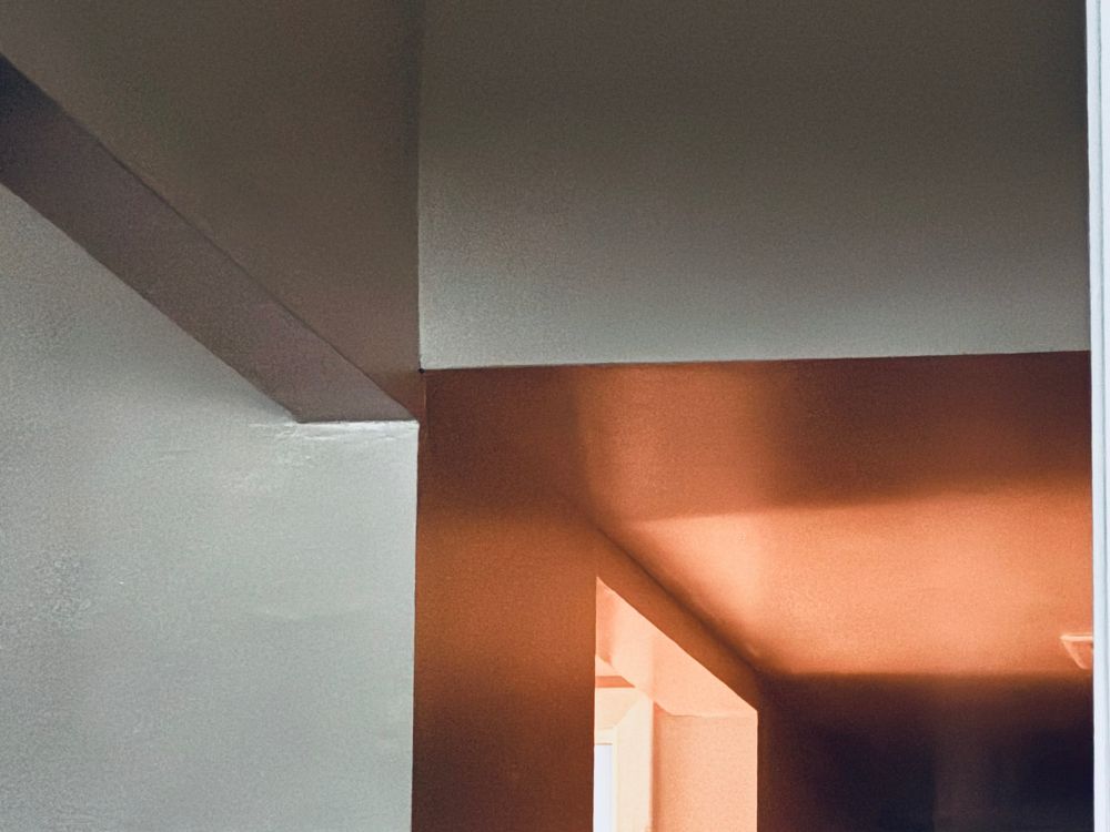 A photograph of right angles, lintels, ceilings, darkness and light, warm and golden in the lower right, cool and gray in the rest 