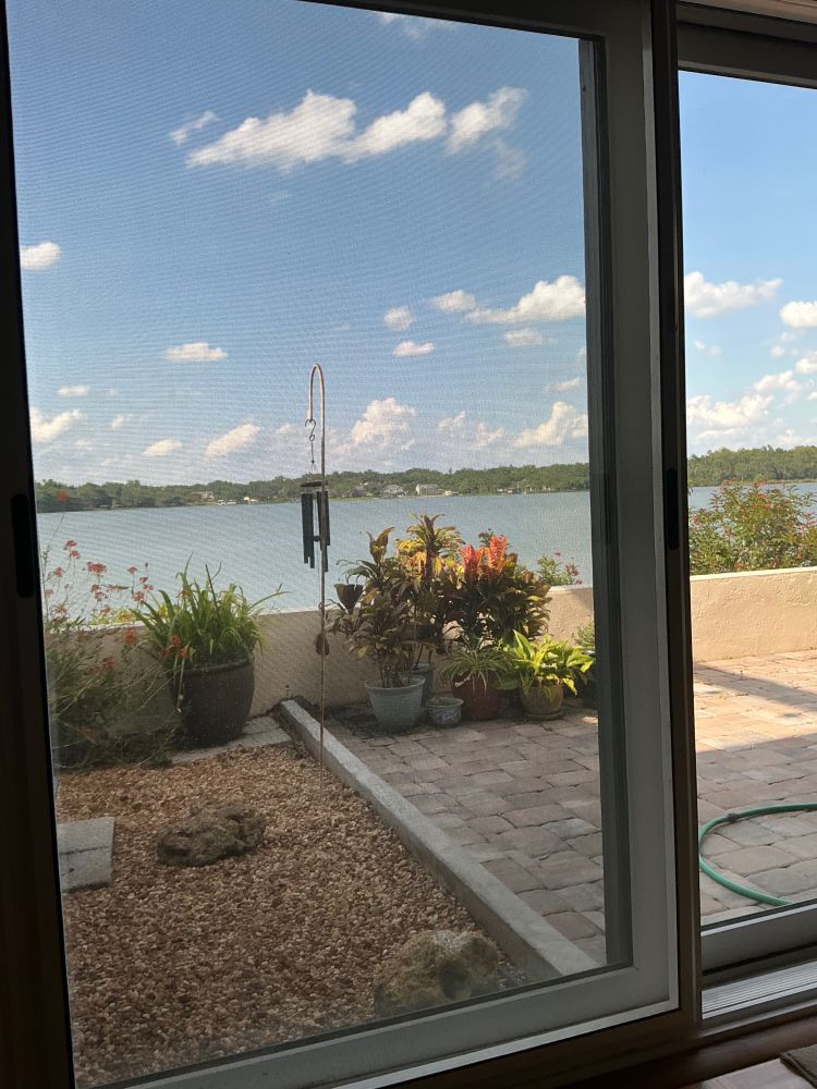 Blue water and blue sky through a sliding door, puffy white clouds a bonus
