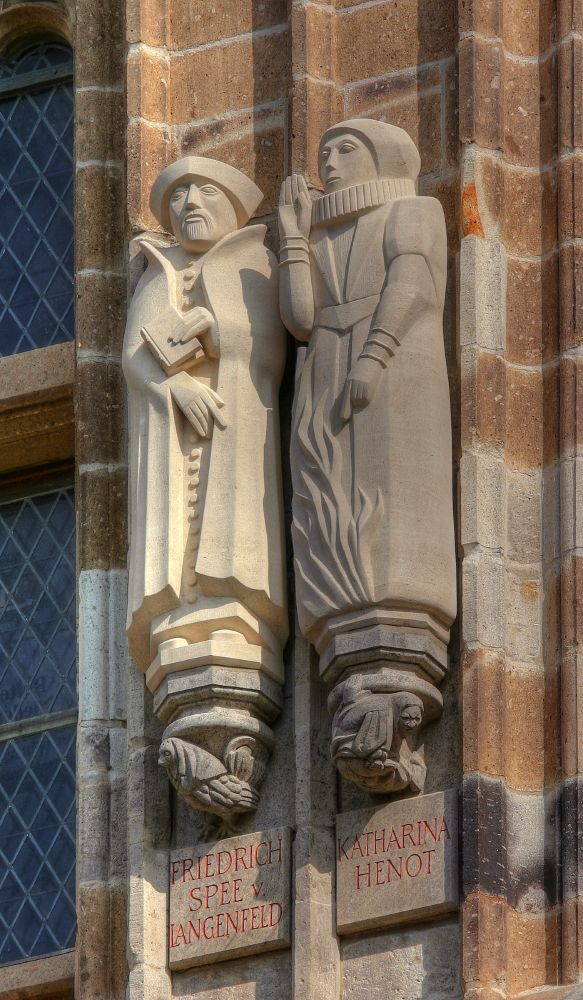 A close-up shot of two statues, one of Friedrich Spree and the other of Katharina Henot, carved into stone. 