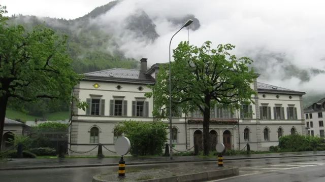 Glarus courthouse with a brightly lit yellow lamp on the top corner. One of the eternal lamps lit in memory of Göldi. 