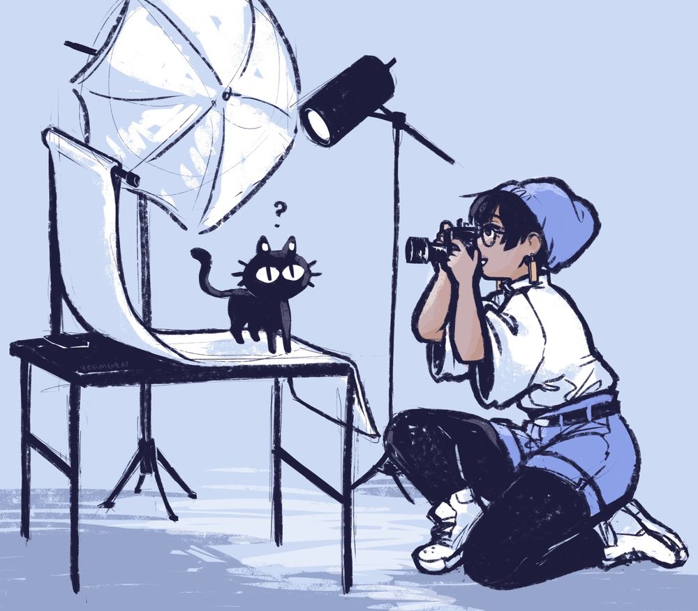 a sketchy drawing of meryl kneeling in front of a mildly elaborate tabletop photo backdrop and lighting kit set up, happily taking a photo of kuroneko, who is standing simply on the backdrop sheet, confused.