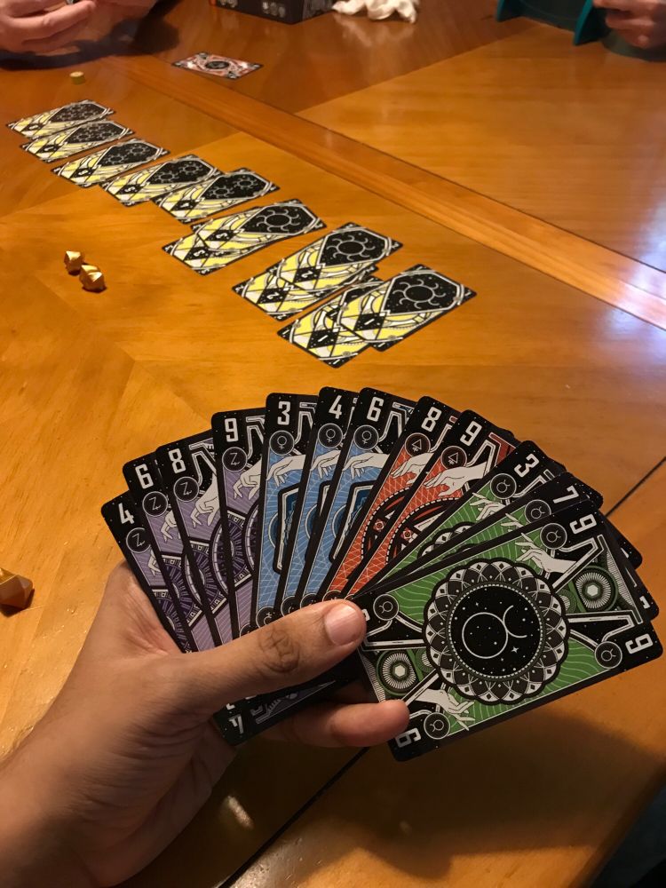 A hand of cards of Aurum and a gold card track is visible in the background