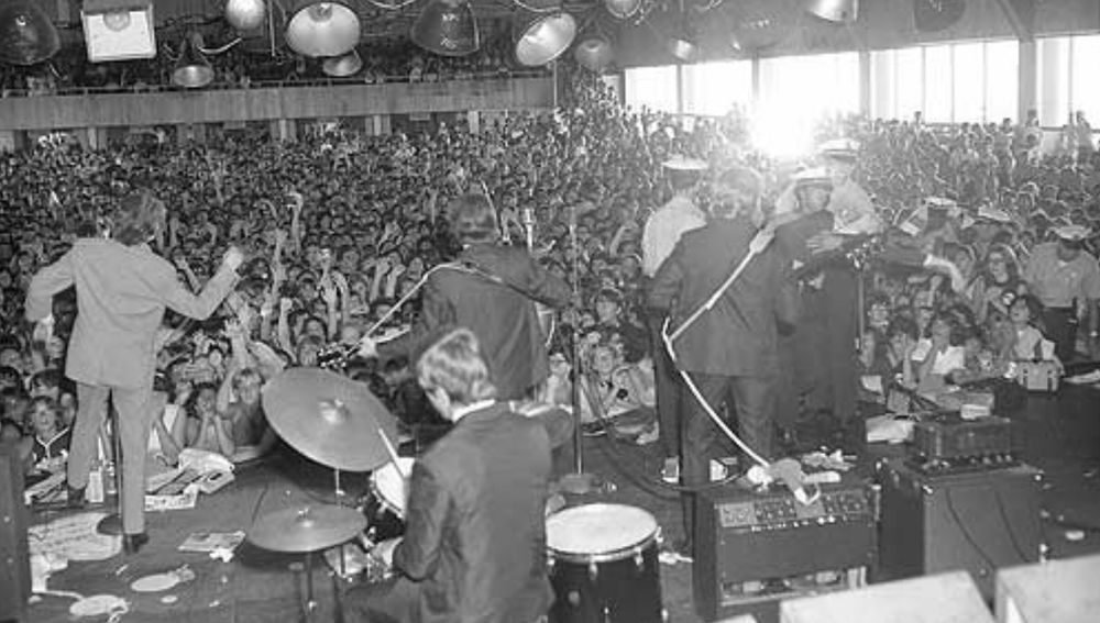 Black and white photo of Hermans Hermits performing in front of a hall packed with 10,000 fans. Atlantic City, New Jersey, August 1965.