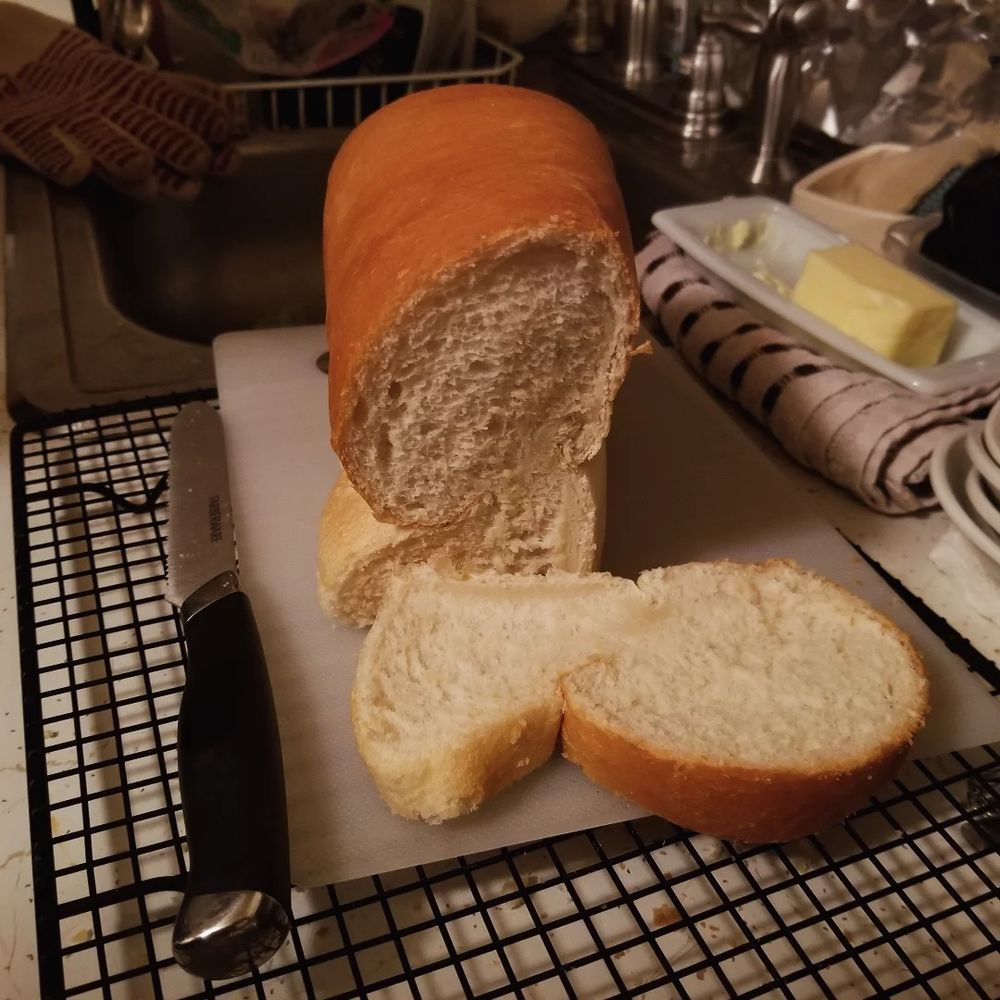 A frontal view of a sliced loaf of bread. The loaf is pinched in the middle from being sliced too soon after coming out of the oven, giving it a very strange shape.