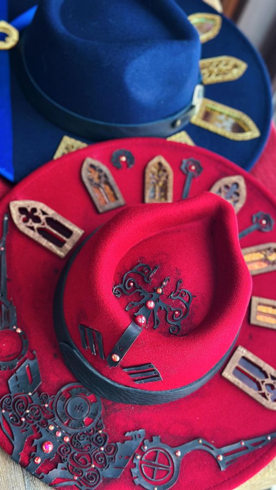 A red felt hat inlaid with tiny stained glass windows and black vinyl decorations.