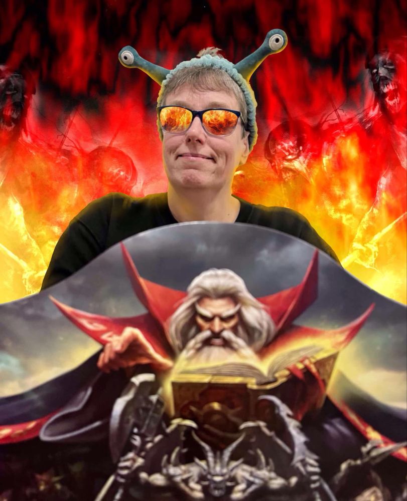 RattusDebicus sits behind the HeroQuest GM Screen as Zargon, the evil wizard! She sports digitally-added mirror shades while flames and evil creatures writhe behind her smiling visage!