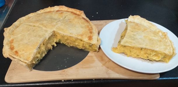 3/4 of a double crust pie with a creamy orange cheesy potato filling with the missing 1/4 placed beside it on a white plate