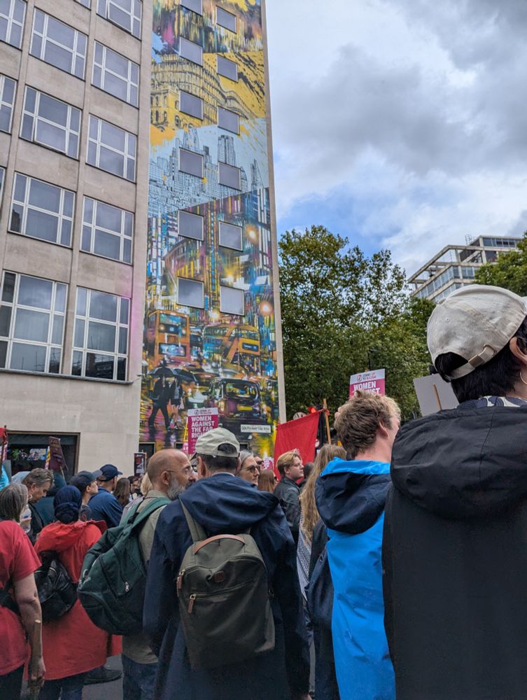 Protesters pass a tall mural