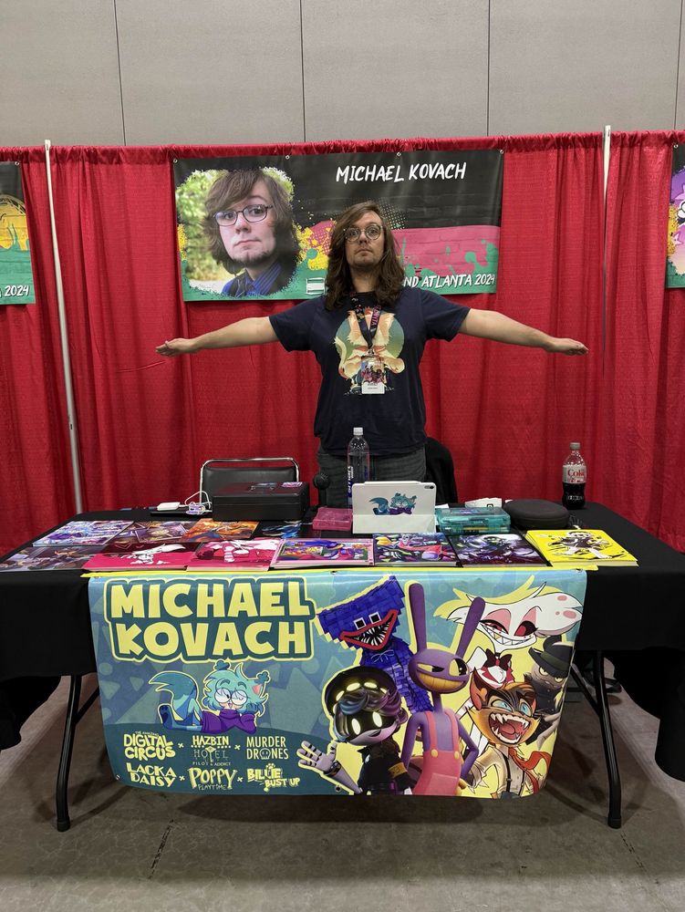 Michael Kovach T-posing behind his table at Anime Weekend Atlanta