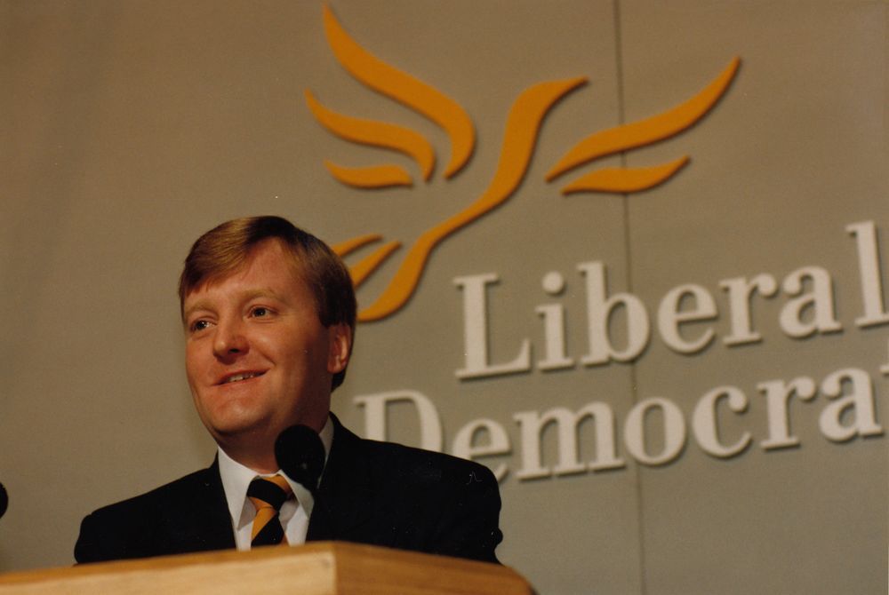 Charles Kennedy, stood in front of the Liberal Democrats logo.