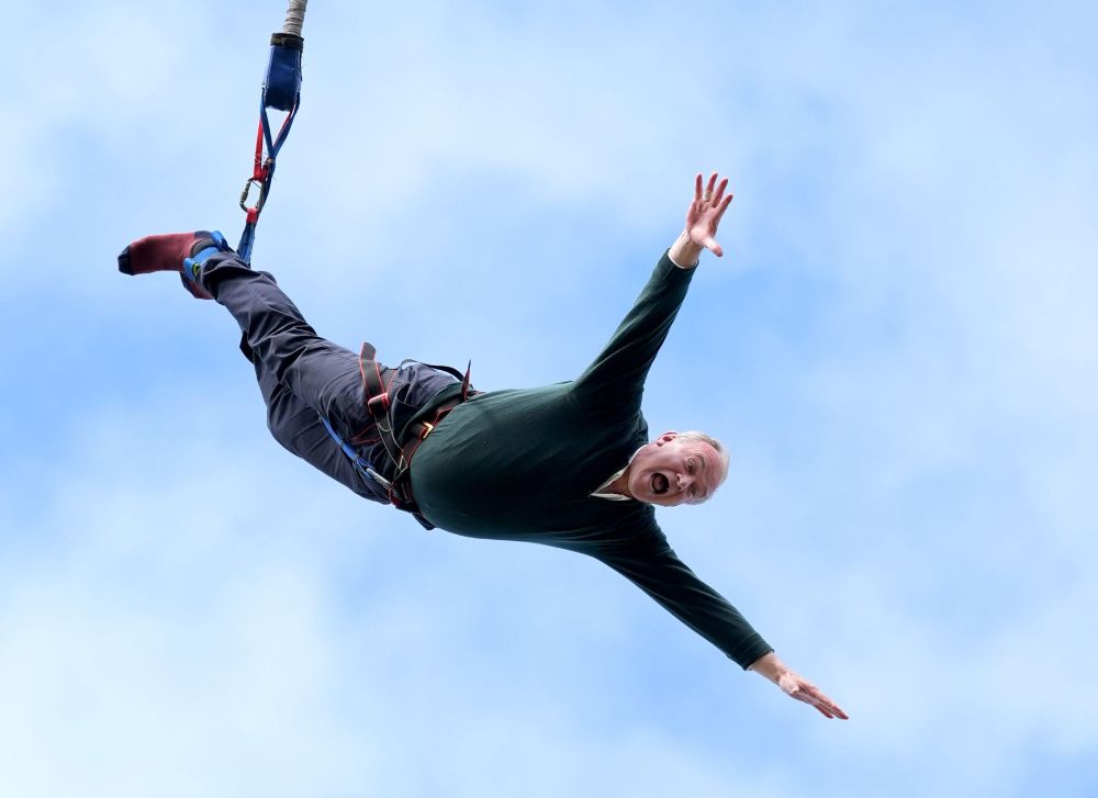 Ed Davey bungee jumping. His arms are spread out wide and his mouth is open.