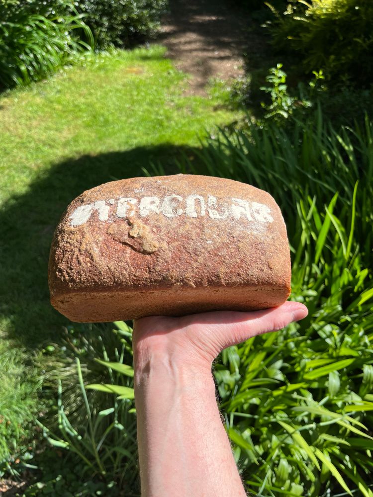 Hand holding up a loaf a bread which has Stereolab baked across the top of the loaf.
