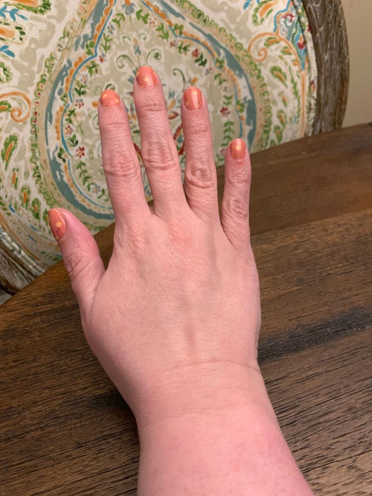 Nails decorated with an orange nude color and little yellow pumpkins