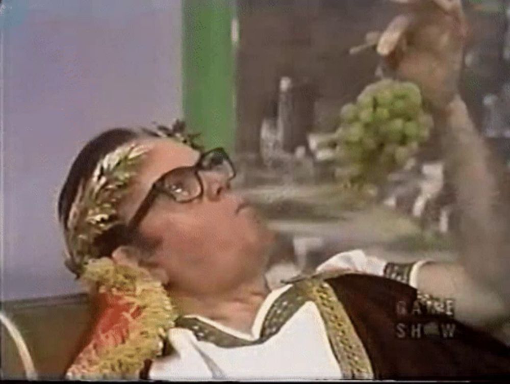 a man wearing glasses and a laurel wreath is laying on a bed and smoking a cigarette