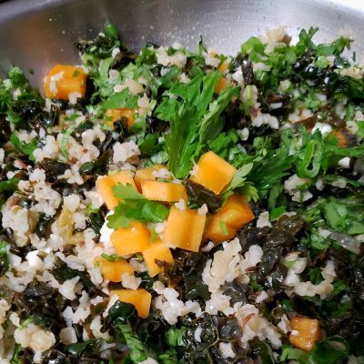 a bowl with a colorful mixed composed salad of bulgur wheat, kale, cilantro, green onion, and diced Fuyu persimmon... seasoned with sauteed onion and garlic, diced green chilies, salt, and lemon juice
