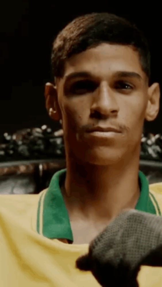 a young man wearing a yellow and green shirt is looking at the camera