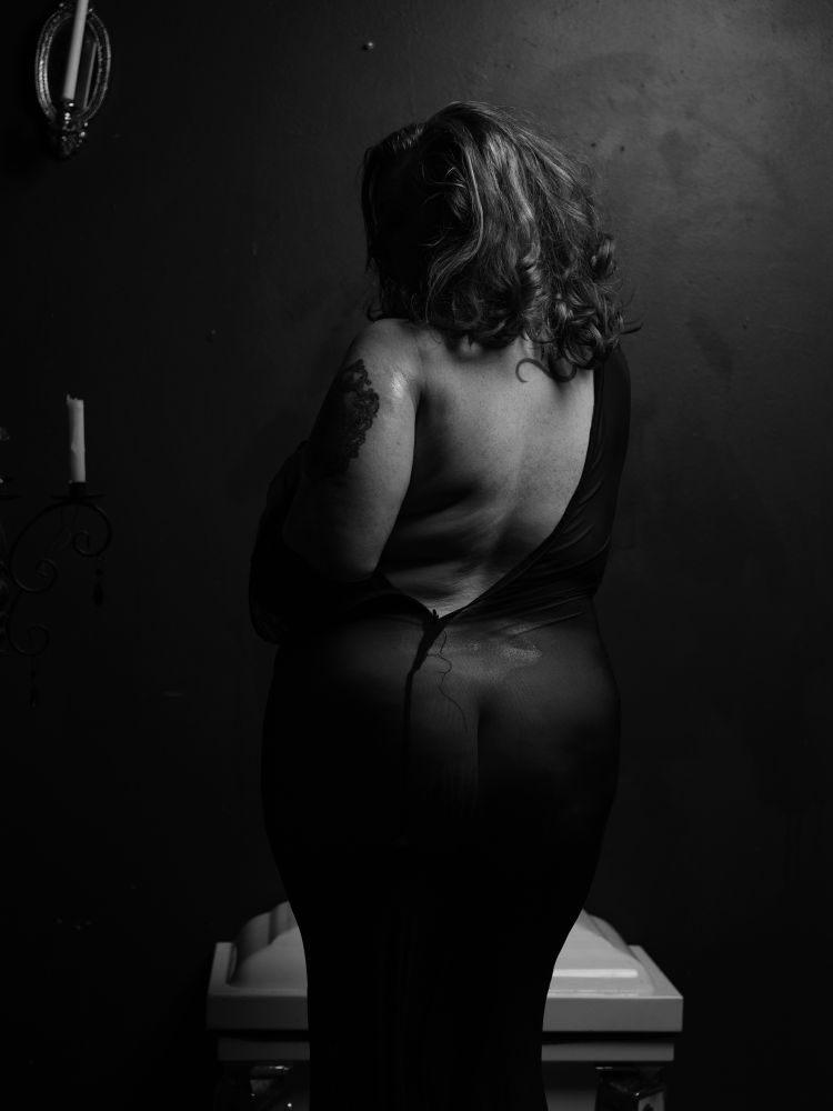 Model with her back facing the camera. Shoulder and back exposed as she removed her wet dress.