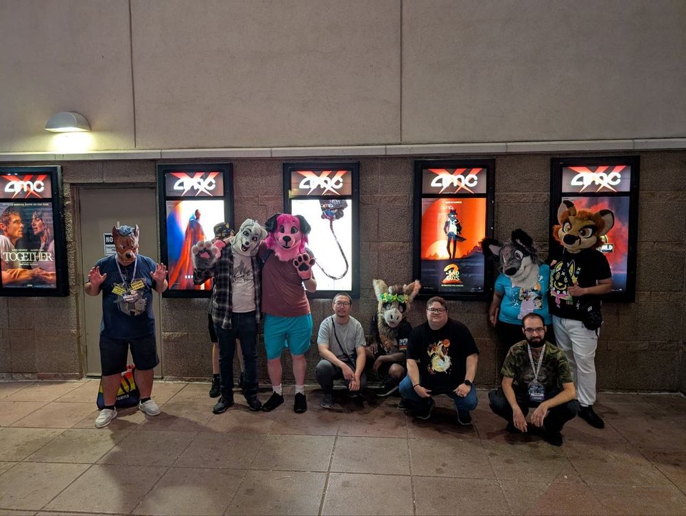 A group of fursuiters posing together in front of the Bad Guys 2 movie poster