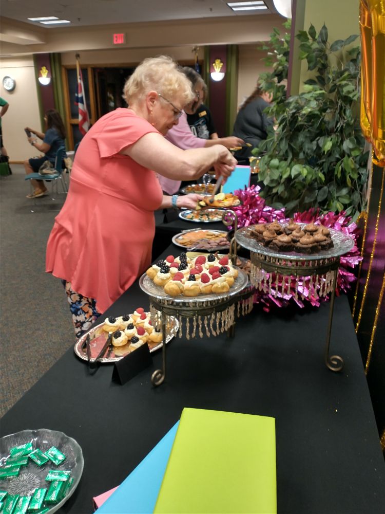 A woman adding food to her plate from a table full of food platters. 