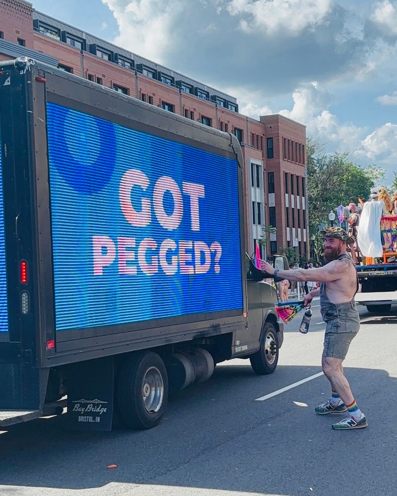 Me pointing at a truck with a digital sign on the side that says “Got pegged?” during pride in Washington DC