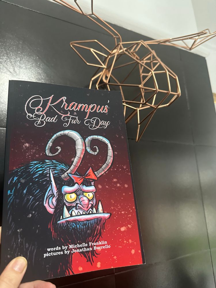 Book Krampus bad fur day cover with a large horned beast on a red background under a wire stags head. 