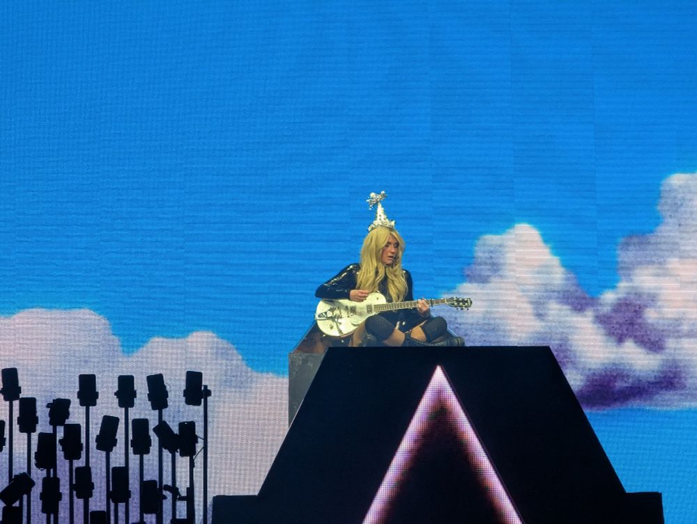Kesha playing guitar with a pointy birthday hat on