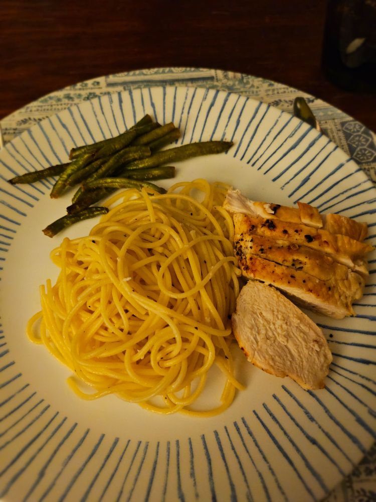 pasta spun and served in the middle of the plate with sliced chicken breast and green beans