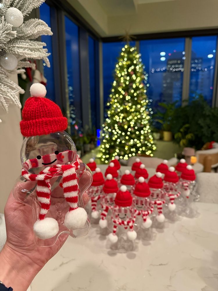 an army of gingerbread cookie shaped bottles with hats and scarves with a Christmas tree in the background