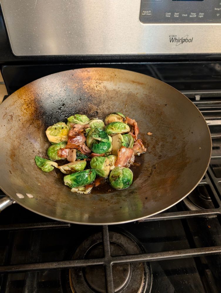 Wok filled with brussel sprouts with bacon and maple syrup