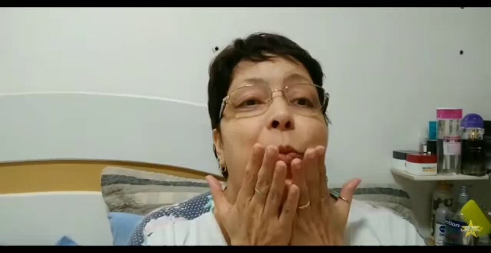 a woman wearing glasses is blowing a kiss while sitting on a bed .