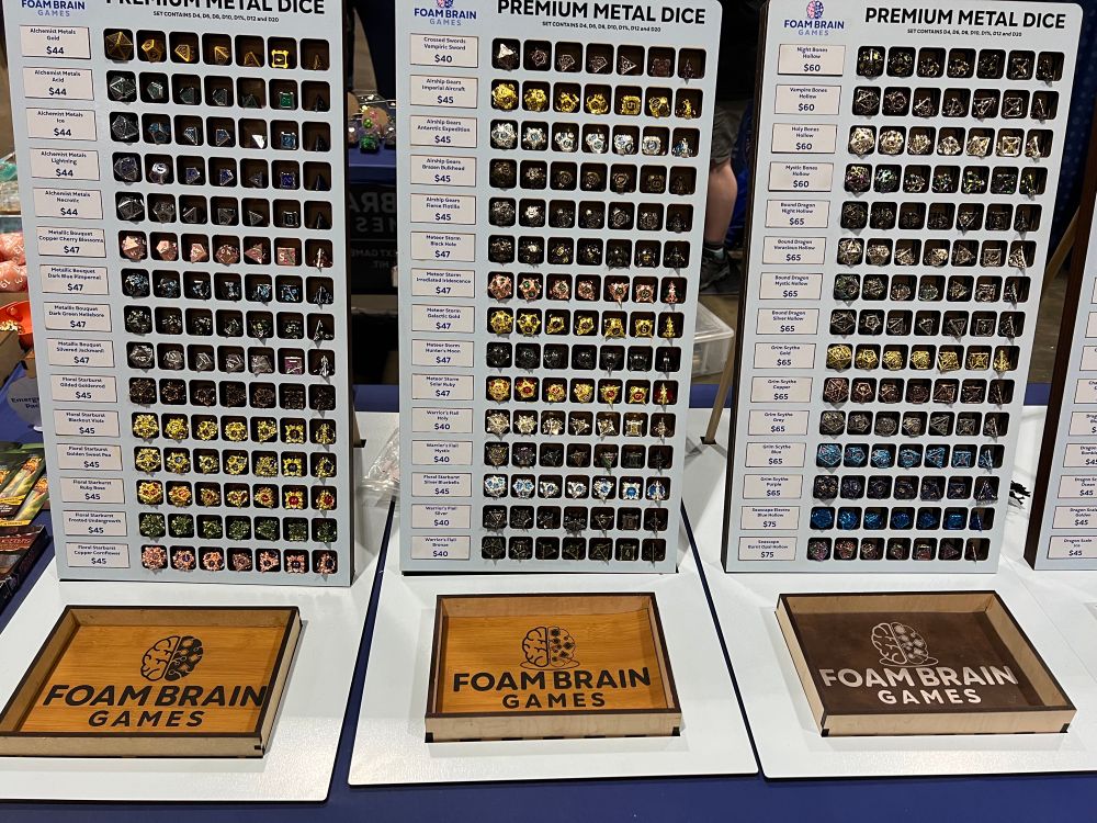 Three racks of 15 dice sets at the Foam Brain Games booth. Priced $40 to $75 each.