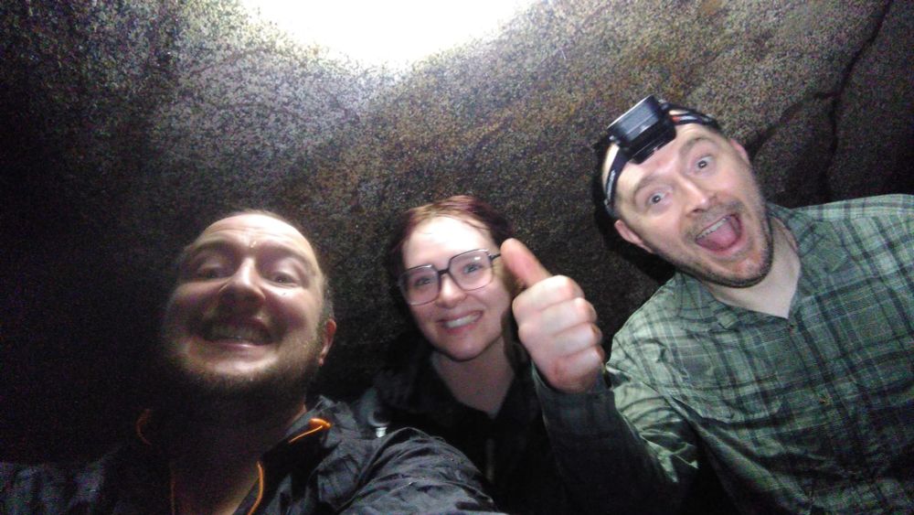 Three amphibian biologists under a rock