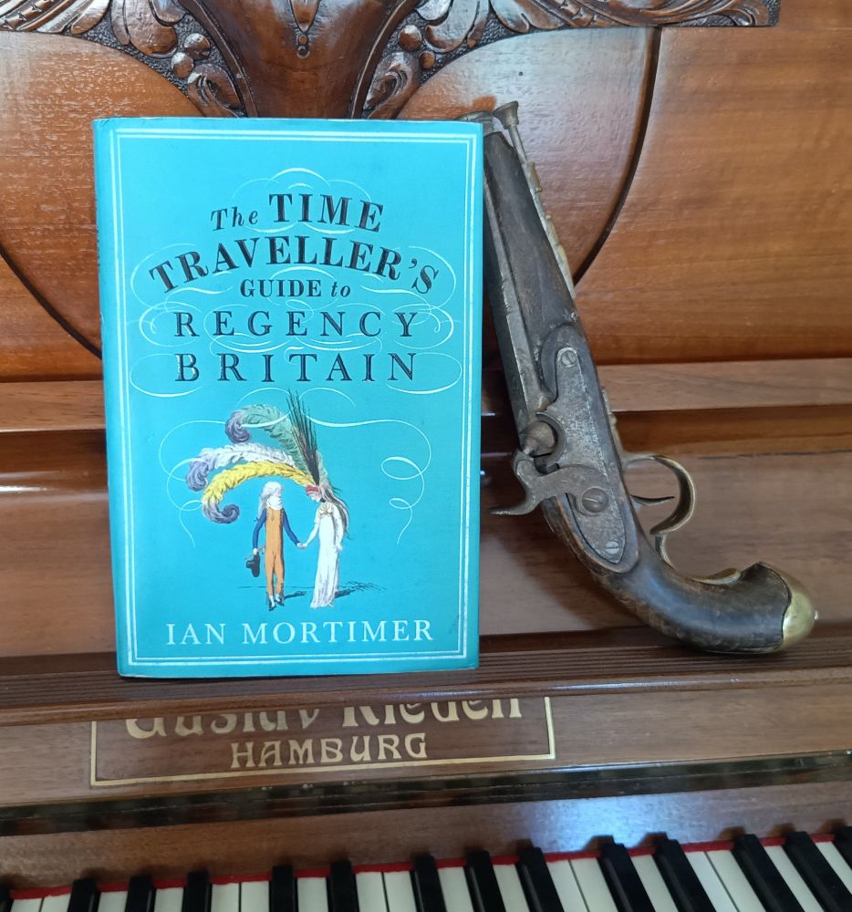 Ian Mortimer's "Time Traveller's Guide to Regency Britain" and a replica of a muzzle loading percussion cap pistol set on an old upright piano.