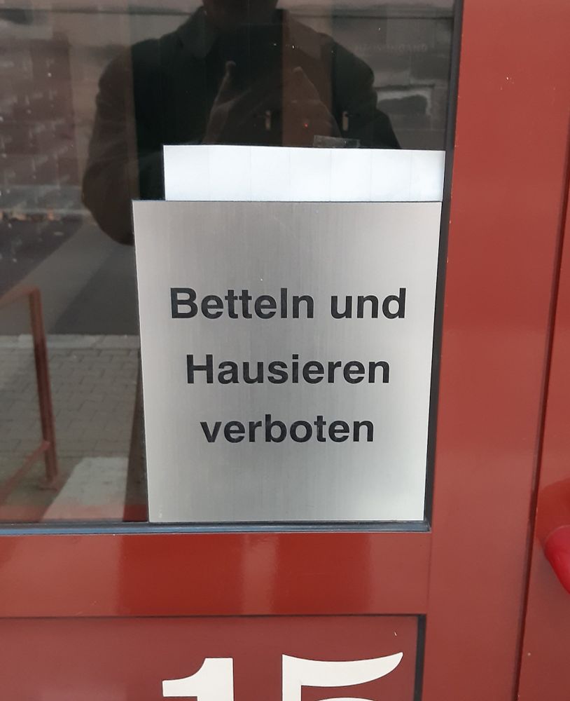 Foto von einer Haustür an dem ein neu aussehendes Schild mit diesem Text hängt.