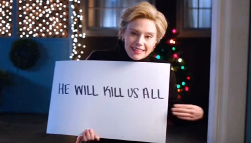 Kate McKinnon as Hilary Clinton, with sign that says 