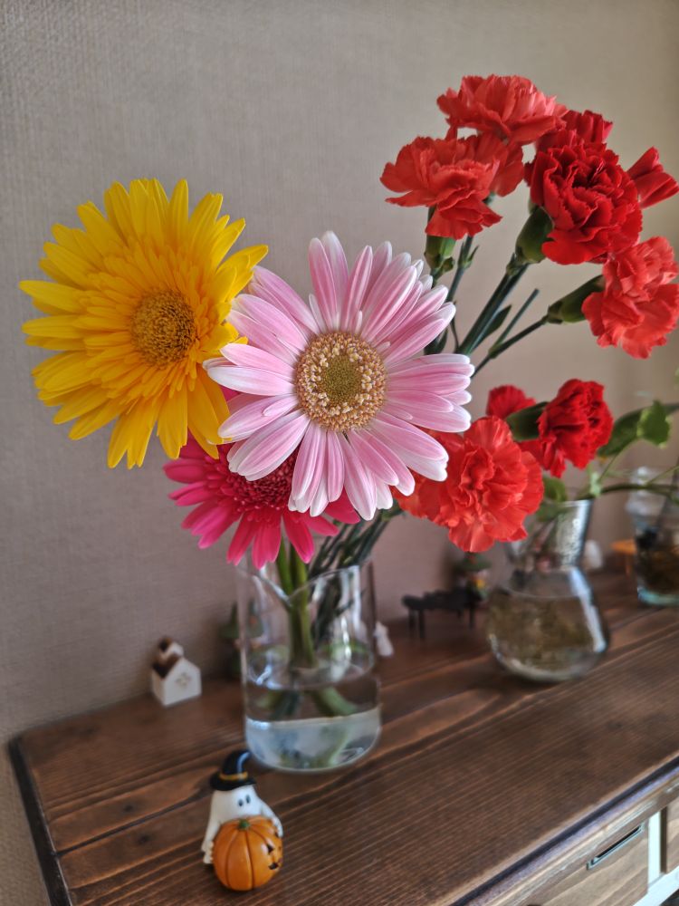 ガーベラとカーネーション、手前にハロウィンのオバケとカボチャの置物、