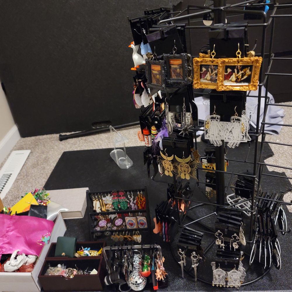 my large earring collection. some earrings hang on a tall spinning rack, some on small desktop racks
