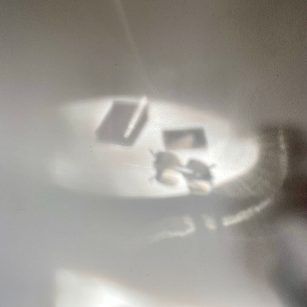 Reflet d’une table en verre sur un mur avec une paire de lunette et un smartphone