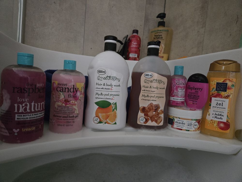 Mehrere Flaschen Duschgel, Shampoo und Badeschaum auf einem Badewannenrand