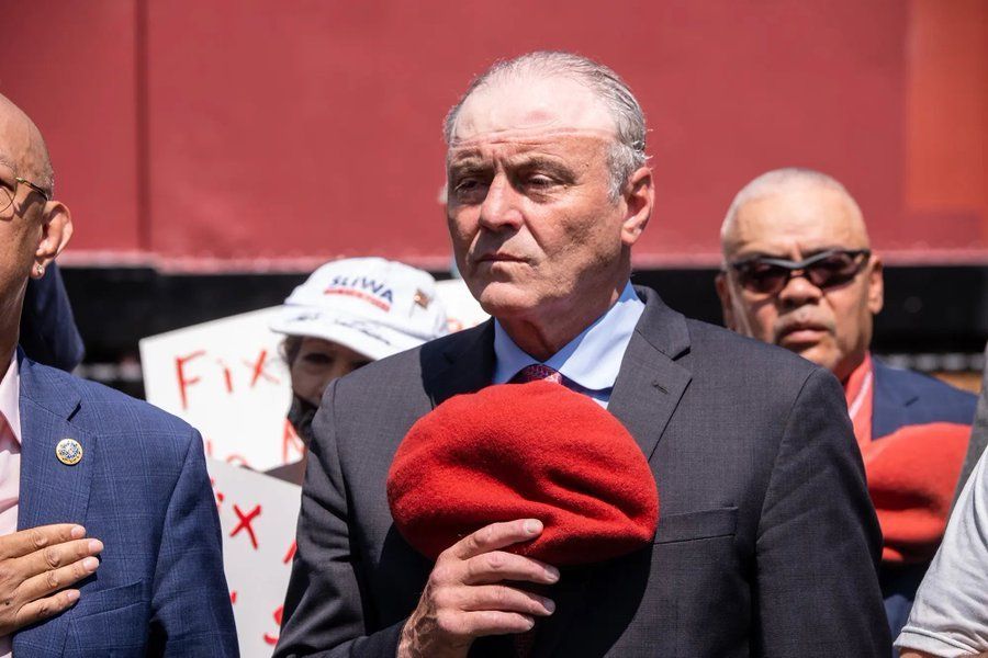 Curtis Sliwa holding his red beret in his hand, a very visible hat tan around his balding head