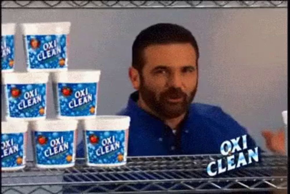 a man is standing in front of a shelf full of oxi clean