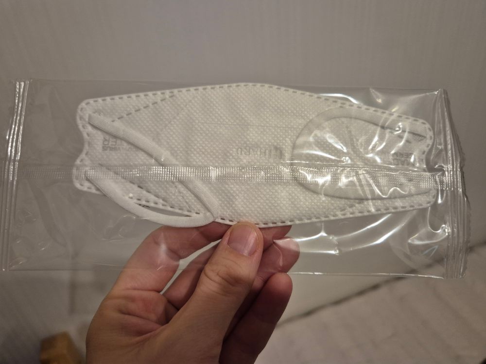 Bild einer Hand, die eine weiße Kindermaske in Fischform hält. 