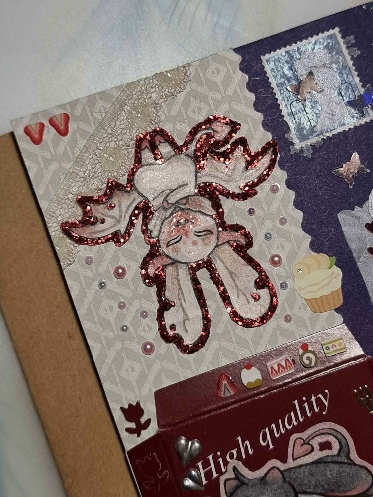 Close up photo of a vamprie character who is hanging upside down like a bat. There's sparkly illustrated blood all around her mouth, she looks satisfied.
