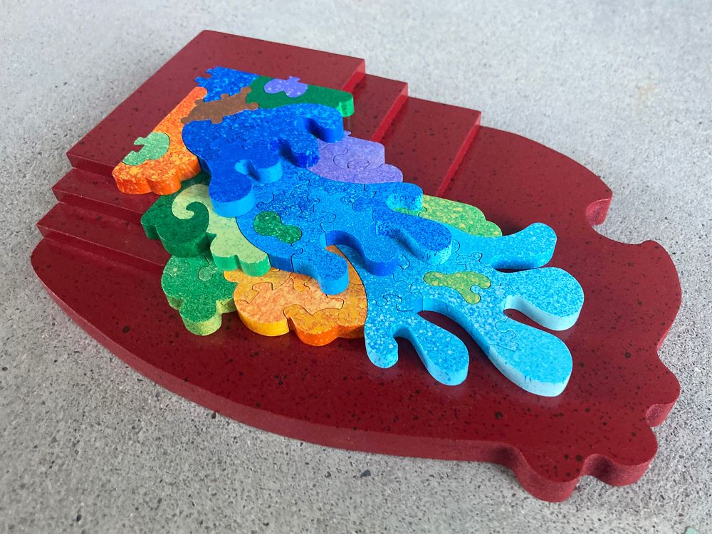 A colorful hand-cut and painted wooden jigsaw puzzle depicting a multi-level waterfall