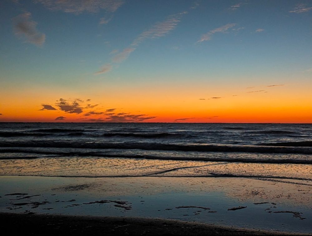 Sunset on a beach with an orange sky and gentle waves