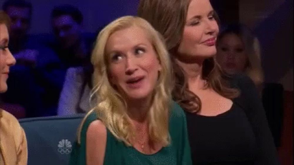 a group of women are sitting in a theatre watching a show and one woman is making a funny face .