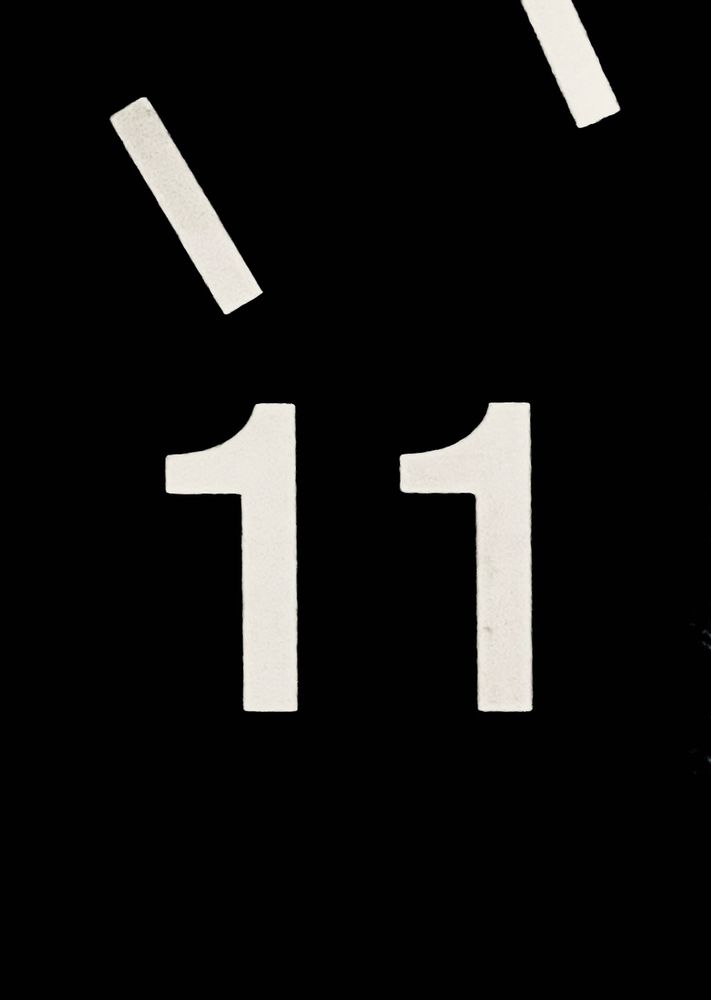 Close up of the number 11 in white on a black clock face. 