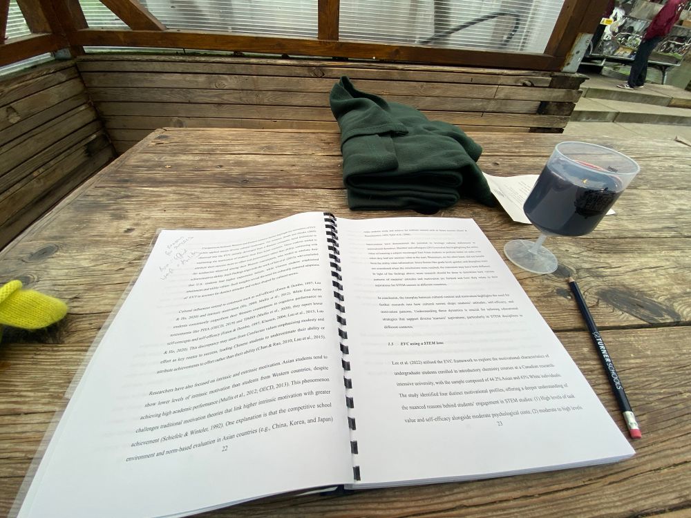 PhD thesis on a table on a bar’s terrace next to a large glass of wine 