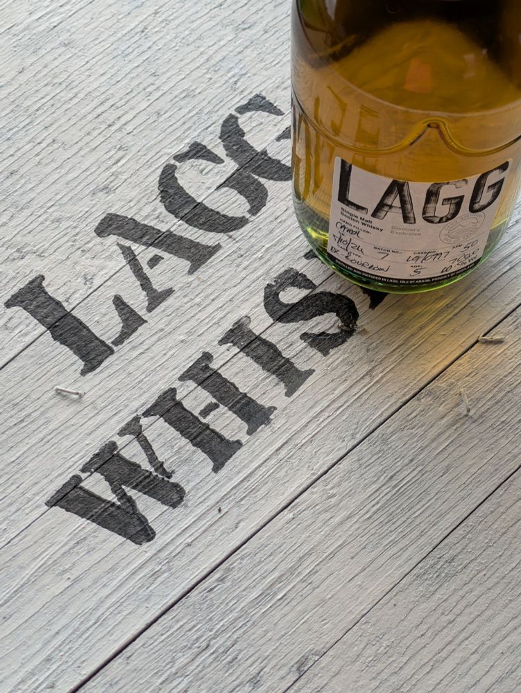 Une bouteille de whisky Lagg sur le dessus d'un fut peint en blanc